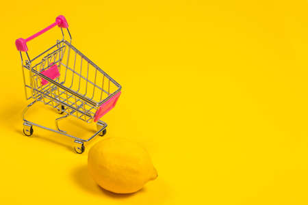 Yellow lemon in a shopping cart on a yellow background, shopping trolleyの写真素材