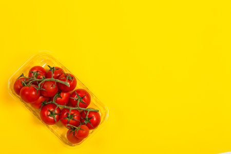 Red cherry tomatoes for salad on yellow backgroundの写真素材