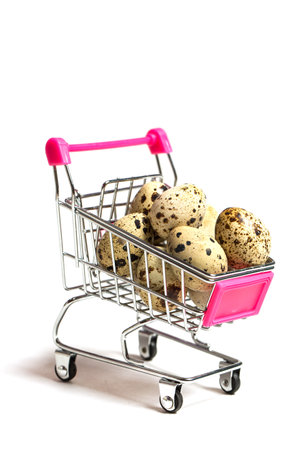 Small quail eggs in a shopping trolley on a white background, healthy foodの写真素材