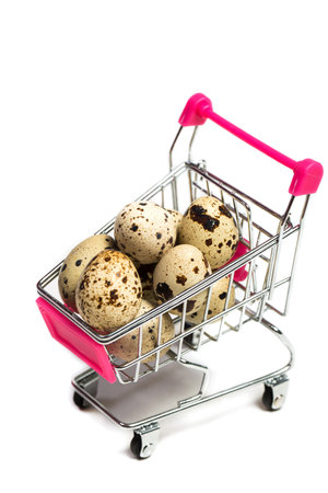 Small quail eggs in a shopping trolley on a white background, healthy foodの写真素材