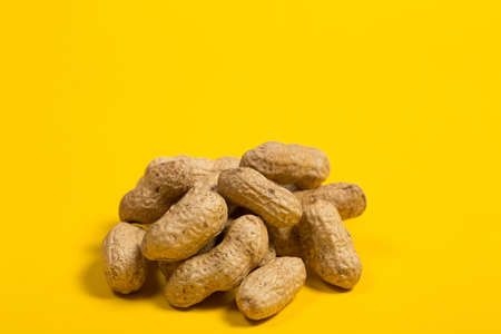 Peanuts in shell on yellow background, healthy foodの写真素材