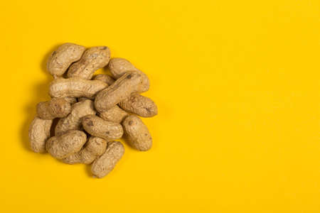 Peanuts in shell on yellow background, healthy foodの写真素材