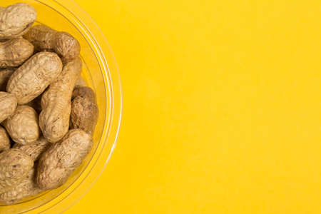 Peanuts in shell on yellow background, healthy foodの写真素材