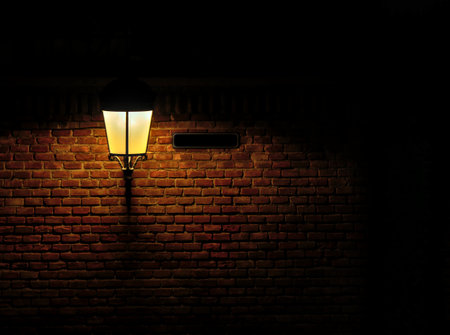 Underexposed and black background with a lantern lighting just its proximity in a dark environment. Free space for an inscription in a sign close to the lamp. Brick wall backgroundの写真素材