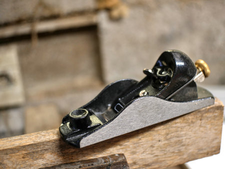 Partially blurred small plane, placed on a board, held by a vice, in a carpentry workshopの写真素材