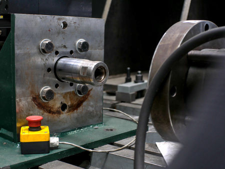 Large steel square with a mechanical coupling part in the center. A slightly blurred emergency stop button in foreground.の写真素材