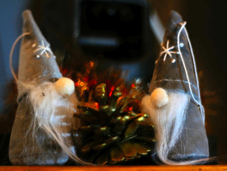 Two little bearded christmas elves around a golden and blurred pine cone