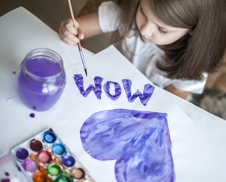 Child making homemade greeting card. A little girl paints a heart  on a homemade greeting card as a gift for Mother Day. Traditional play concept. Arts and crafts conceptの写真素材