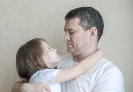 Portrait of cute little girl held in father's arms. Happy loving family. Father and his daughter child girl playing hugging. Cute baby and daddy. Concept of Father day. Family holiday and togethernessの写真素材