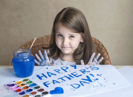 Child making homemade greeting card. Painted hand. A little girl paints a heart on a homemade greeting card as a gift for Father Day. Finger paint. Traditional play concept. Art and craft conceptの写真素材