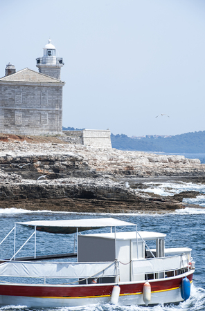 Beautiful historical stone house and tower of white lighthouse on the seashore. Elements voyage. Seascape. Bird flies over the seaの写真素材