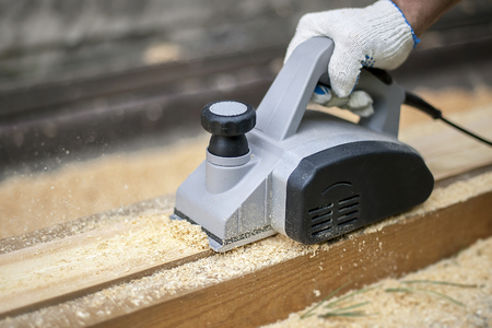 Man planing boards with electric tools, chips flying in all directions. Construction, wood processingの写真素材