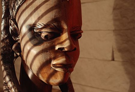 Ancient wooden sculpture from Africa on a sunlight. A head of the woman.の写真素材