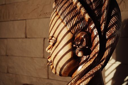 Ancient wooden sculpture from Africa on a sunlight. A head of the woman.の写真素材