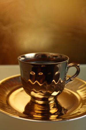 coffee in gold cup on a glass tableの写真素材