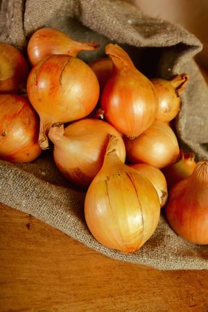 onion in rough bag on a old wooden tableの写真素材
