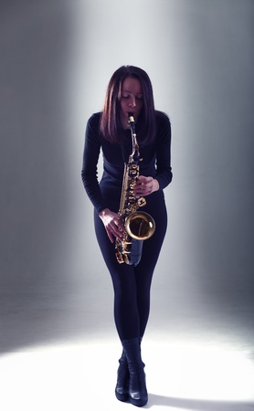 young woman in black with saxophone.の写真素材