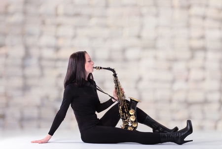 young woman in black with saxophone.の写真素材