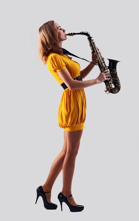  woman with saxophone on a grey background.の写真素材