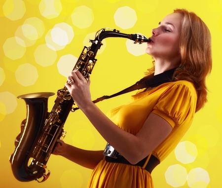 young woman in yellow dress with saxophone.の写真素材