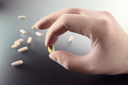 Hand in rubber glove with pill.の写真素材