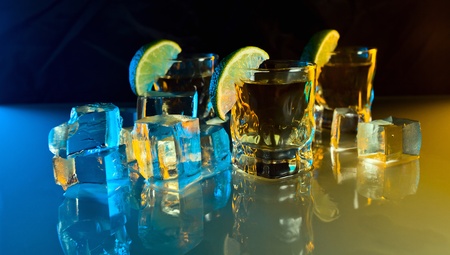 tequila , lime and ice on a glass table.