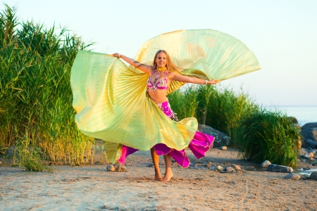 beautiful girl in east dress on seacoast before a sunsetの写真素材