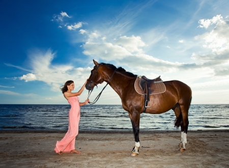 beautiful girl in dress with horse on seacoastの写真素材