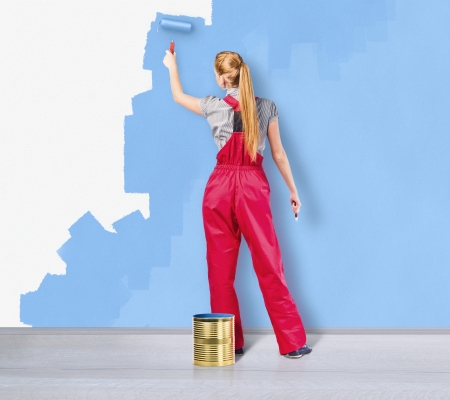 Young woman in red overalls with painting tools の写真素材