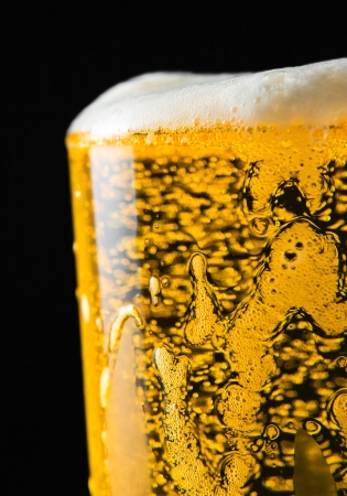 Beer glass with froth over black backgroundの写真素材