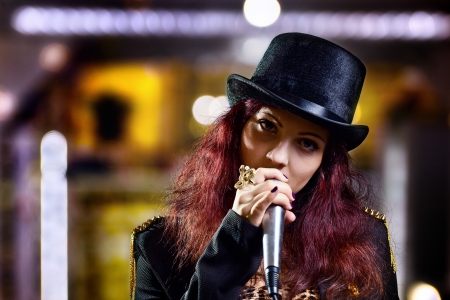 girl in black hat with microphone in nightclub