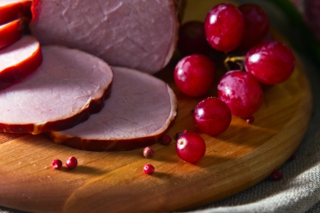 smoked meat and red grape on a wooden boardの写真素材