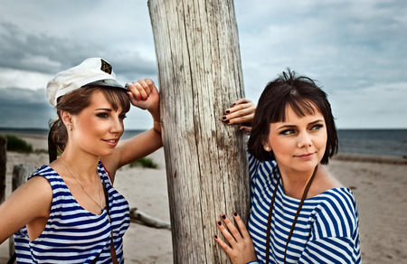 Two girlfriends in striped vest on a beachの写真素材