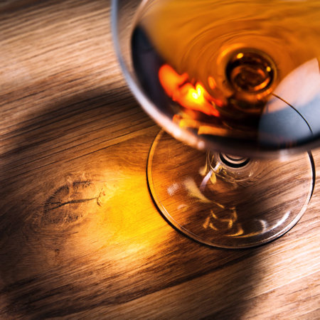 snifter with brandy on old oak table, focus on table