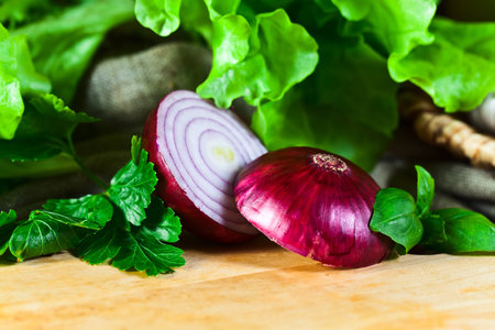 red onion and greens on kitchen tableの写真素材