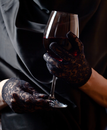 woman in black gloves with glass of red wine の写真素材