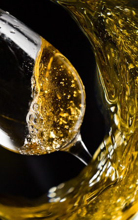 sweet wine being poured into a wineglass on black backgroundの写真素材