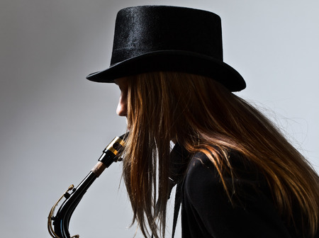 young beautiful woman in black hat with saxophoneの写真素材