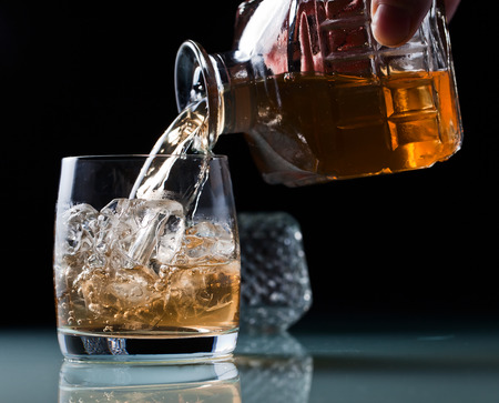 glass with whiskey and ice on a glass table の写真素材