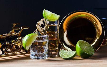 saxophone and tequila with lime on wooden tableの写真素材