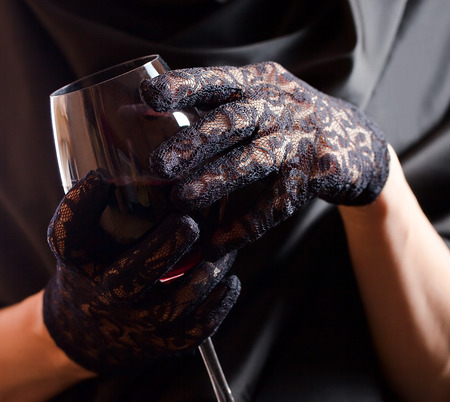 woman in black gloves with glass of red wine の写真素材