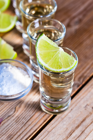 gold tequila with salt and lime on old wooden table.の写真素材