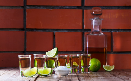 gold tequila with salt and lime on old wooden table.の写真素材