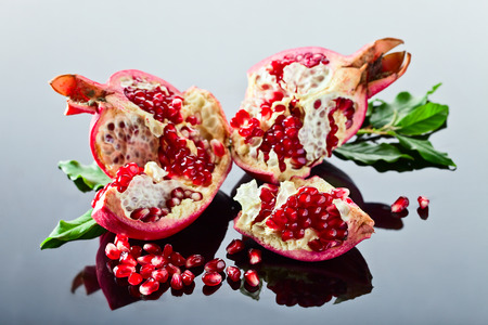 ripe pomegranate on a black glass tableの写真素材