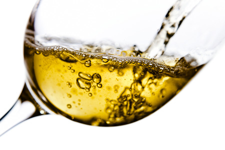 White wine being poured into a wineglass, isolated  on white backgroundの写真素材