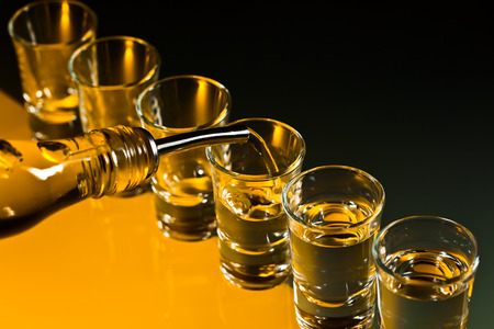 Glasses with an alcoholic drink on a glass tableの写真素材