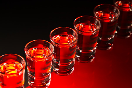 Glasses with an alcoholic drink on a glass tableの写真素材