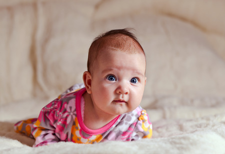 The surprised  little girl on soft beige blanket
