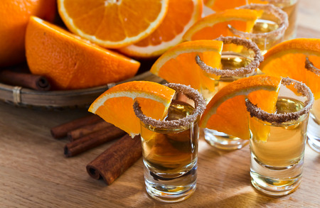 tequila with orange and cinnamon on a wooden tableの写真素材