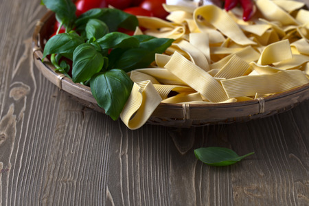 uncooked noodles with basil and vegetables on wooden tableの写真素材